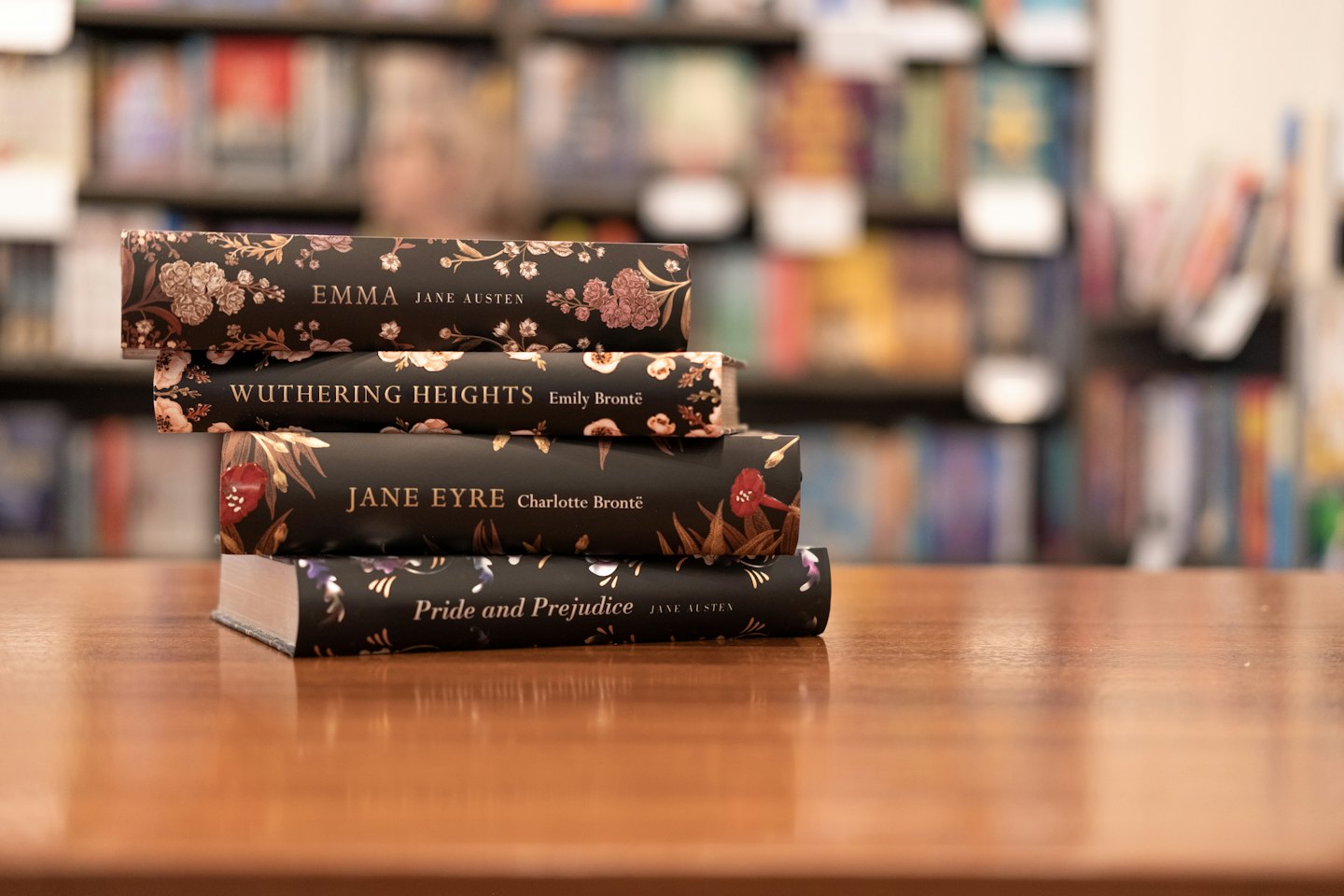 Quattro libri di letteratura classica impilati su un tavolo di legno.