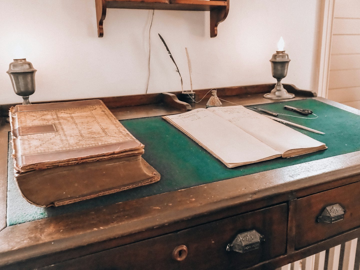 Scrivania antica con libri, penne d'oca e lampade.